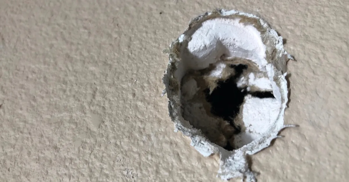 A doorknob-sized hole punched through a textured drywall wall
