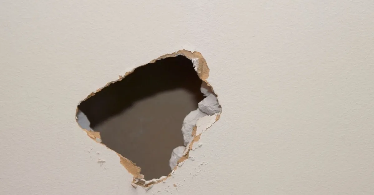 A jagged hole punched through an interior drywall wall