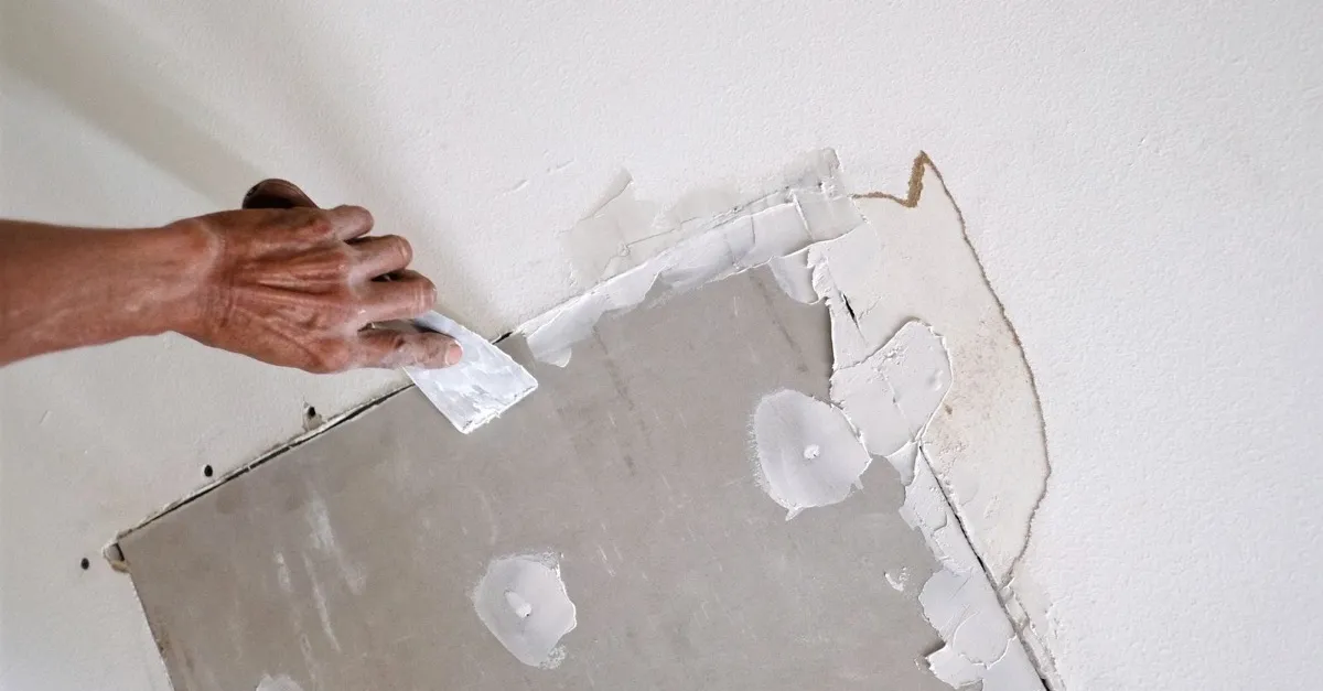 Taping and mudding the seams around a new drywall patch set into a wall