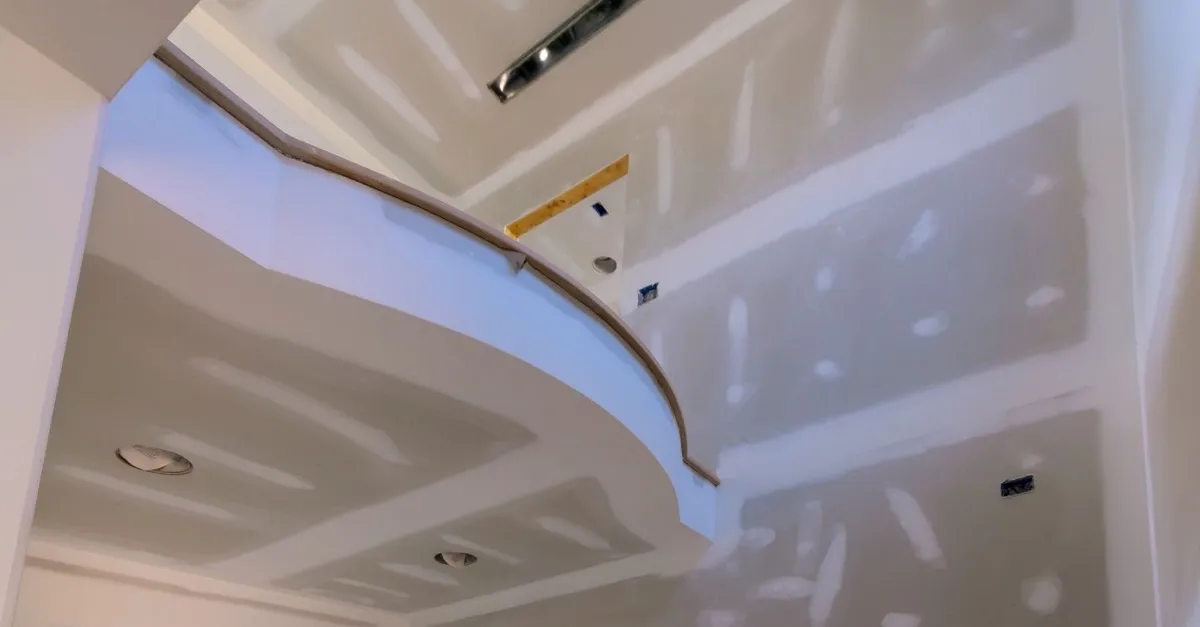 A vaulted ceiling and curved wall with drywall hung and the seams mudded
