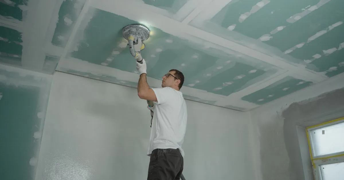 A worker repairing a ceiling after water damage